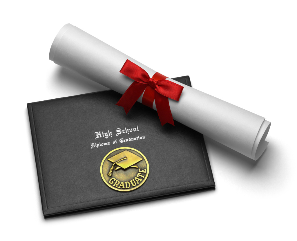 A high school diploma tied with a red ribbon lays diagonally across a black diploma holder with the words High School Diploma of Graduation in white stylized font above a gold seal with a graduation cap and the word graduate in all capitalized letters.