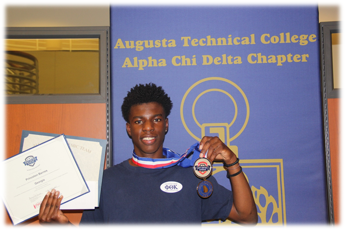 African American male, Princeton Barnes smiles, holding his certificates in his right hand and his medals in his left hand while standing in front of a blue violet poster labelled Augusta Technical College Alpha Chi Delta Chapter in gold font. 