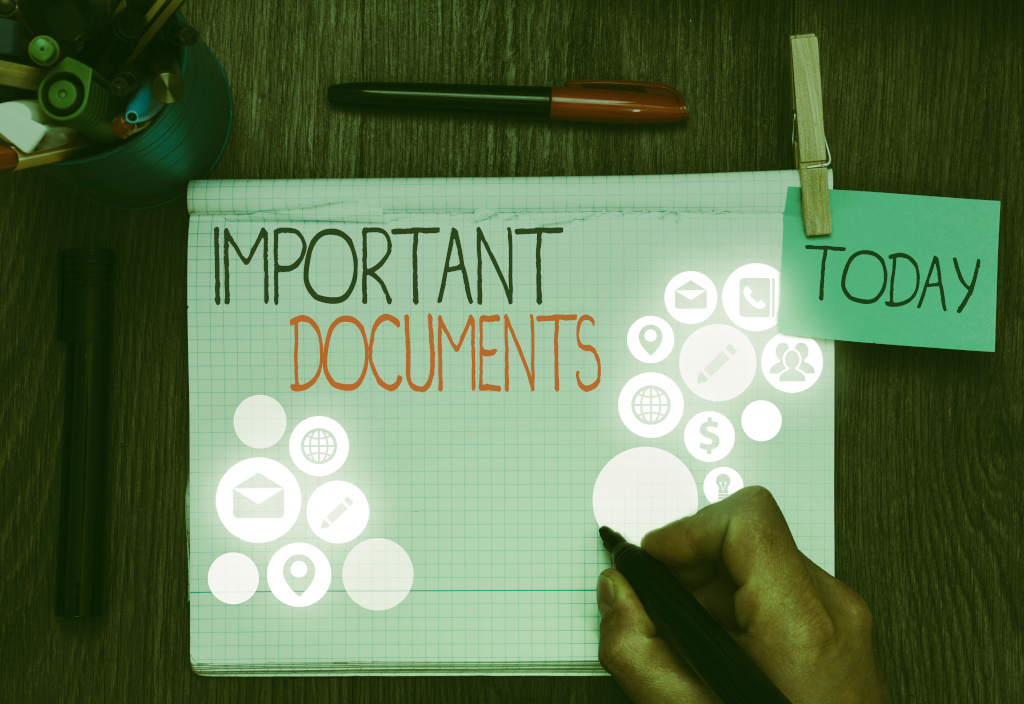 The word Important is in black font above the word Documents in red font on graphic paper. White light circles with various symbols are displayed on the left and right of the page and a green sticky note with the word today is clipped to the right of the page. A hand holds a black marker and a red and black marker sits above the notebook with a pencil holder on the left.