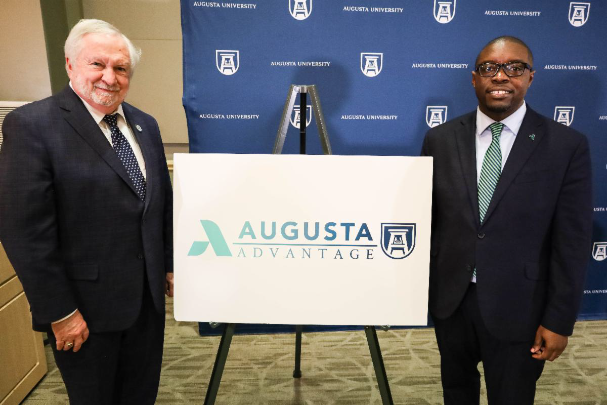 President Keel, an older Caucasian male wearing a black suit with a white collared shirt and navy blue tie stands to the left of the Augusta Advantage logo whild President Whirl, an African American male wearing a black suit, white collared shirt and light blue tie stands to the right.