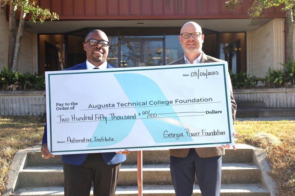 Dr. Jermaine Whirl and Mr. Kerry Bridges holding a check for Two Hundred and fifty thousand dollars standing on the steps of the 100 bldg.