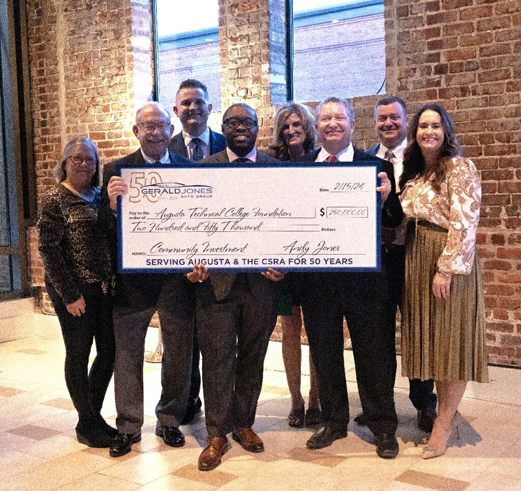 Dr. Jermaine Whirl stands with Andy Jones and other representatives of Gerald Jones Auto Group holding a check for $250,000.