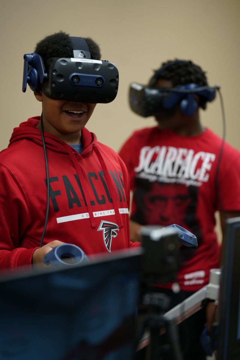 An African American male smiles wearing VR equipment.