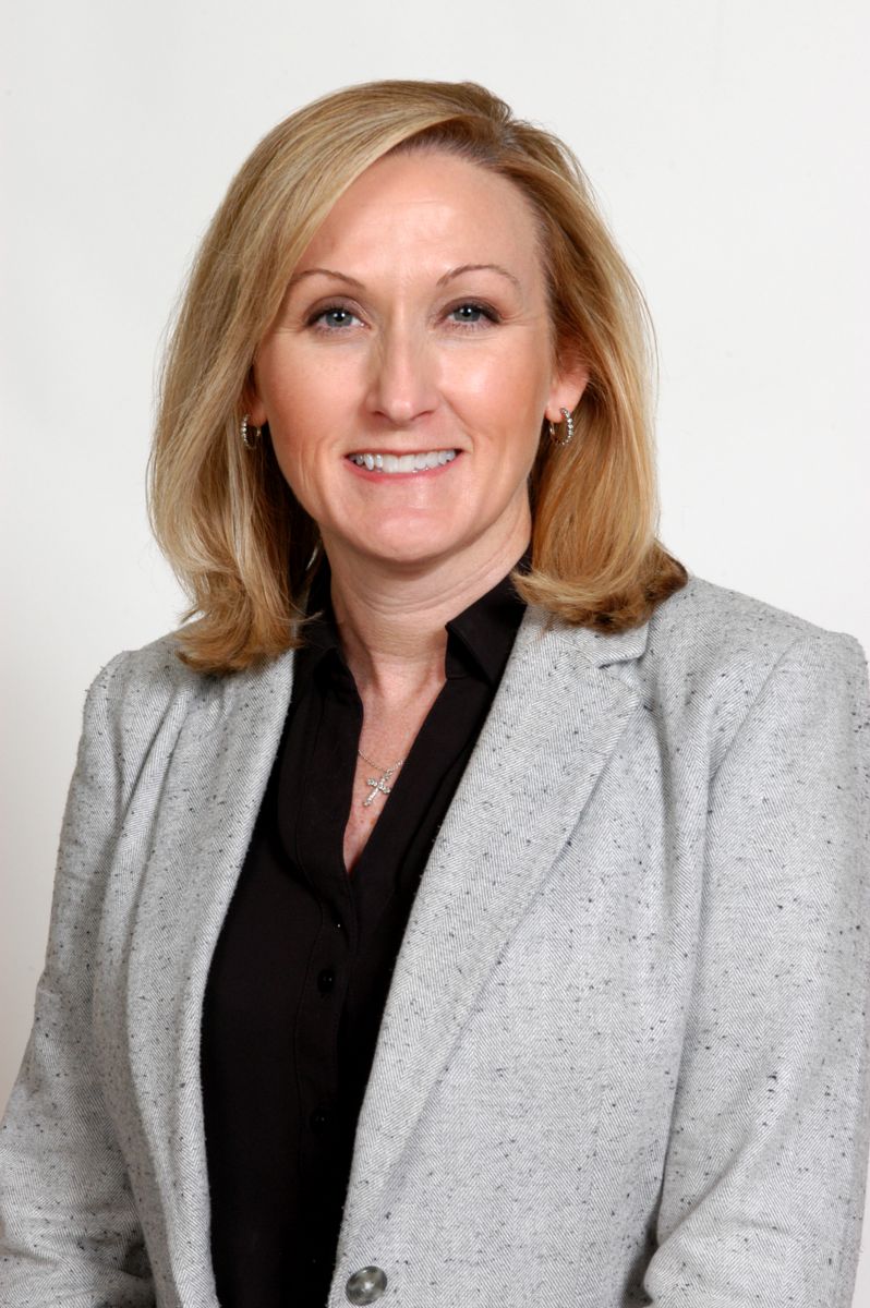 Mrs. Nikki McClain, a Caucasian female wearing a gray jacket and a black blouse with a light gray background.