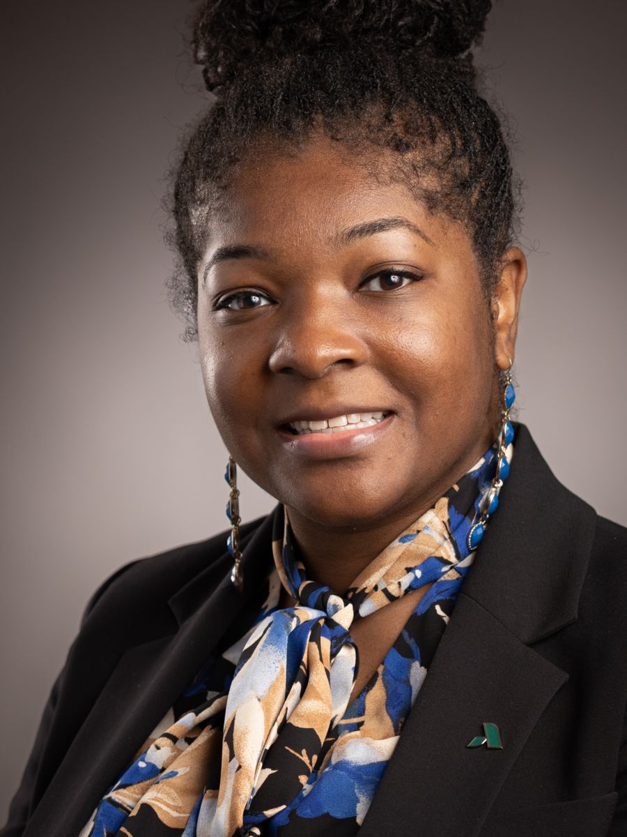 Ms. Aherial Polite, Dean for Arts and Sciences, smiles wearing a multi-colored dress top with a black dress jacket.