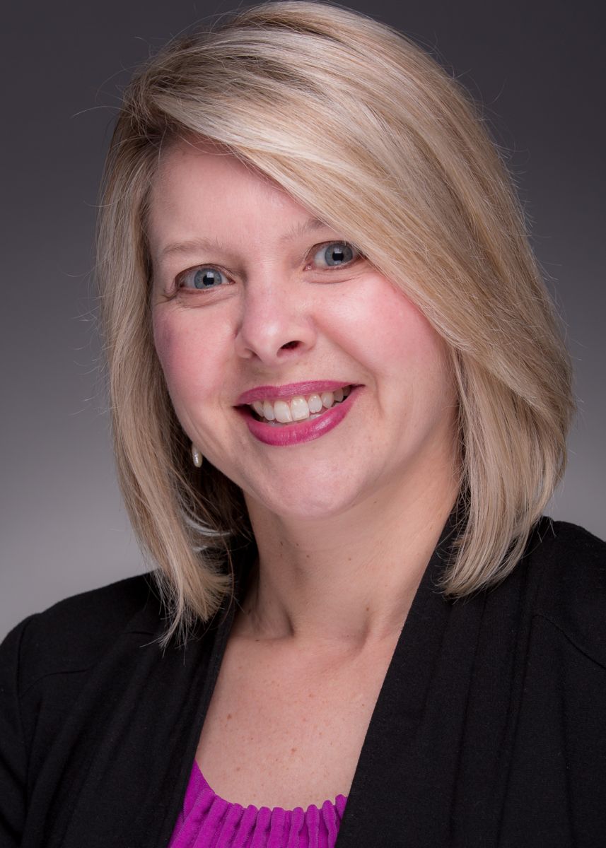 Mrs. Julie Langham, a Caucasian female with shoulder length blonde hair, smiles wearing a fuchsia top with a black dress jacket.